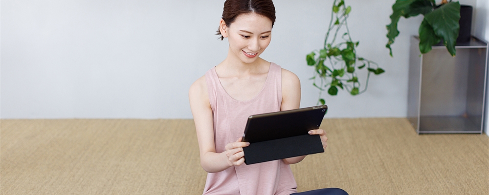 Young person sitting in a yoga studio smiling and looking at a tablet