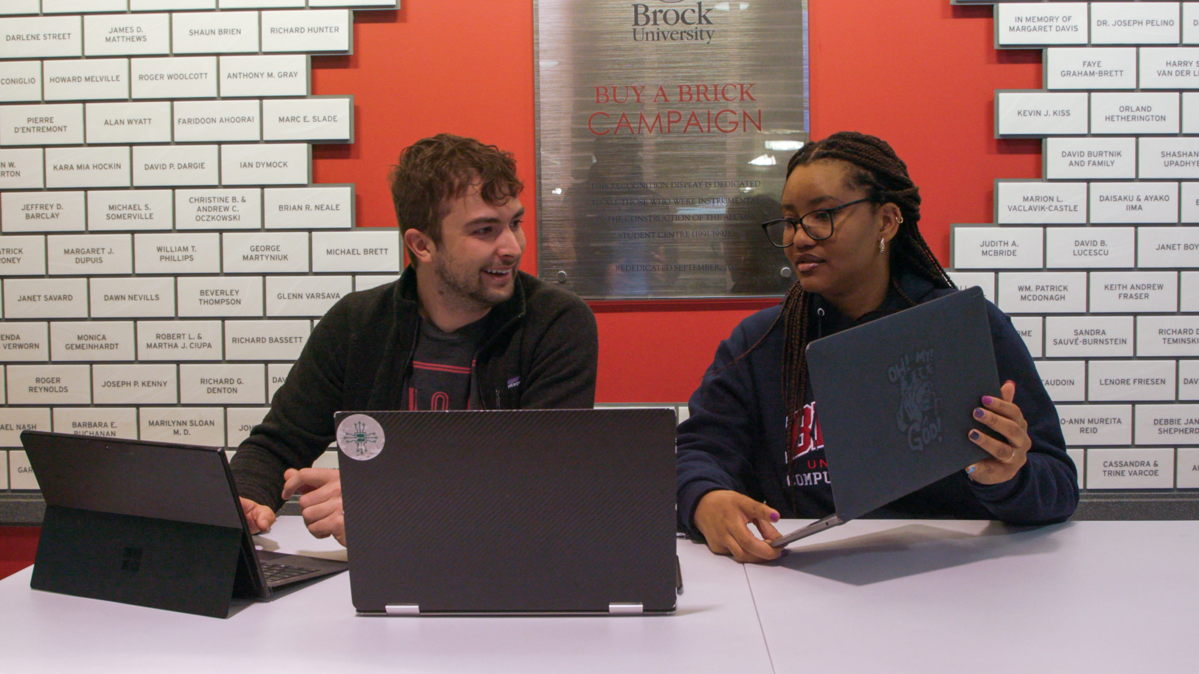 Two students talking by laptops